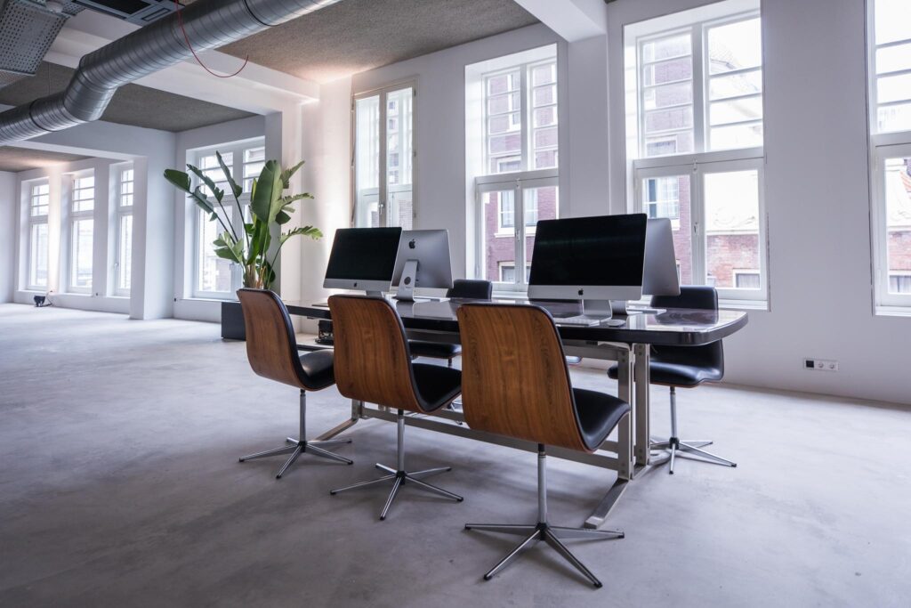 Modern kantoorinterieur aan de Prins Hendrikkade met werkplekken, iMac-computers en grote ramen.